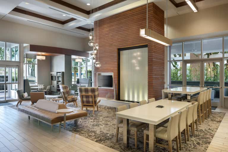 Contemporary lobby with exposed wood beams, dining table, fireplace, and natural lighting