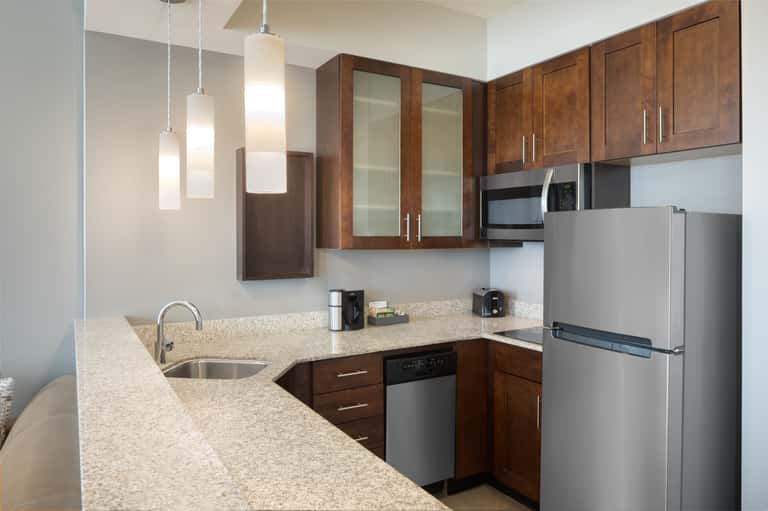 Studio kitchen with dark wood cabinets, quartz countertop, stainless steel appliances