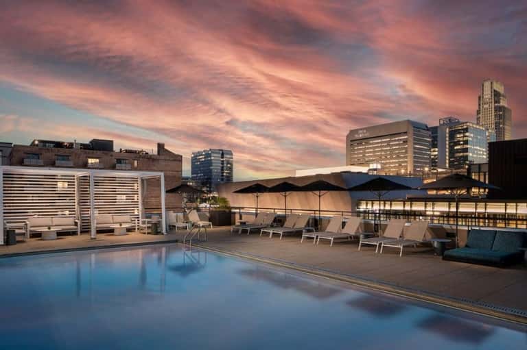 Elevated rooftop pool at dusk with city lights and urban skyline backdrop