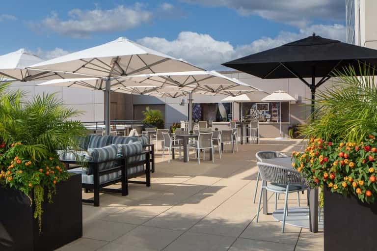 Modern rooftop terrace with white umbrellas, lounge seating, and flowering planters