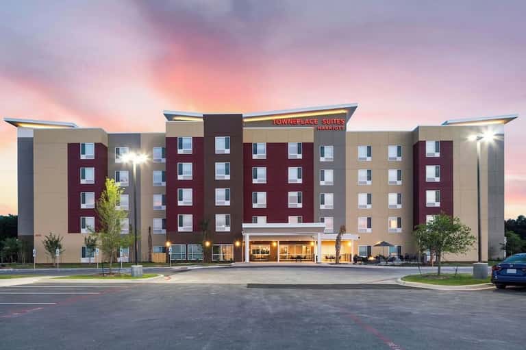 Towneplace Suites hotel exterior at dusk with burgundy and beige facade, lit entrance, and parking lot