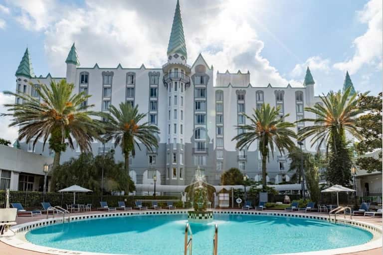 Grand white castle-style hotel with turrets and palm trees, featuring circular pool