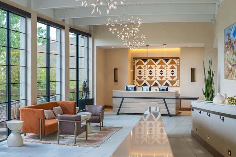 Modern hotel lobby with geometric patterned artwork, check-in desk, and suspended light fixture