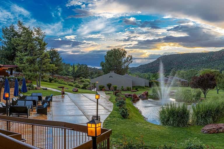 Luxury resort grounds with manicured lawns, fountain, chapel structure, and mountain vistas