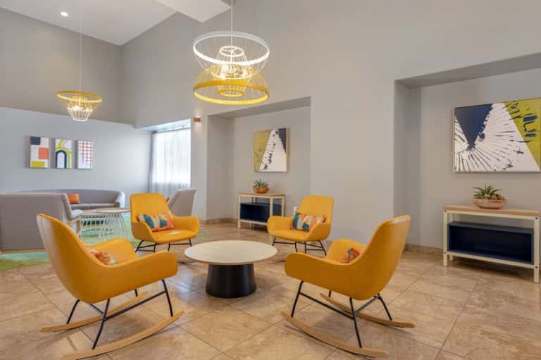 Bright lobby seating area with yellow chairs, geometric pendant lights, and modern decor