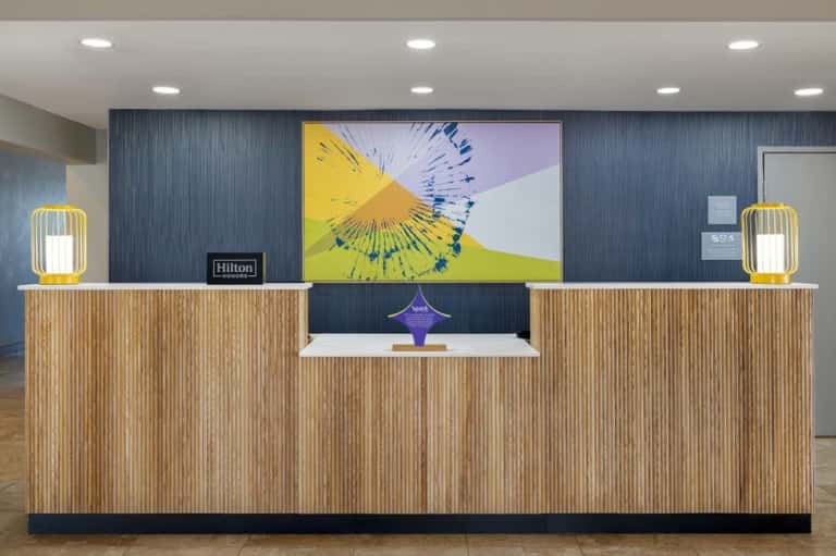 Hilton hotel check-in desk with wooden slat design, dark blue accent wall, and abstract yellow artwork
