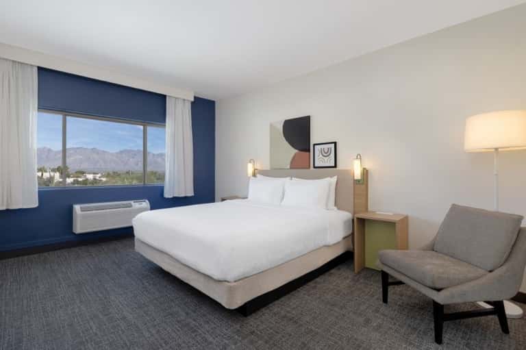 Hotel bedroom with mountain view, navy accent wall, white bedding, and contemporary furnishings