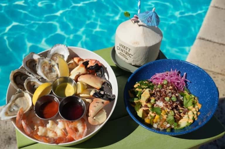 Poolside dining with seafood platter, colorful salad bowl, and tropical cocktails at Hyatt Centric resort