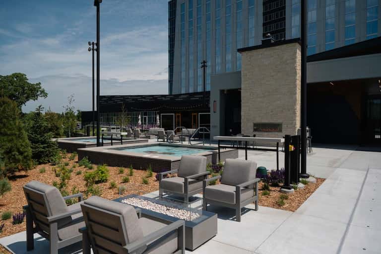 Rooftop pool and fire pit lounge with modern hotel building, landscaping, and evening ambiance