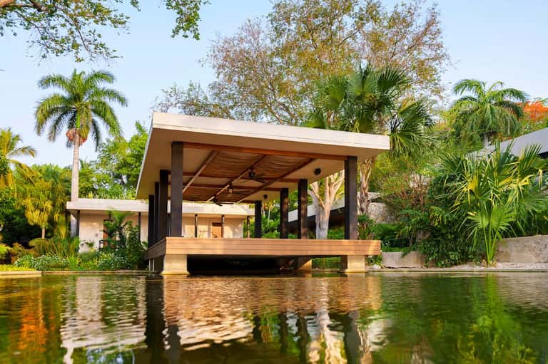 Modern waterfront pavilion with dark wood accents and concrete supports overlooking natural water feature