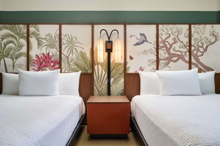 Twin beds with decorative botanical headboard panels, floor lamps, and neutral bedding
