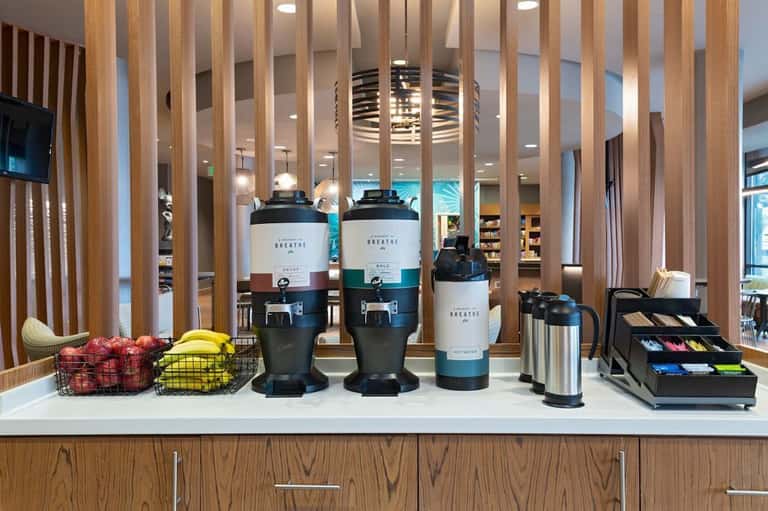 Coffee bar counter with brewing equipment, wooden slat dividers, fresh fruit, and beverage supplies