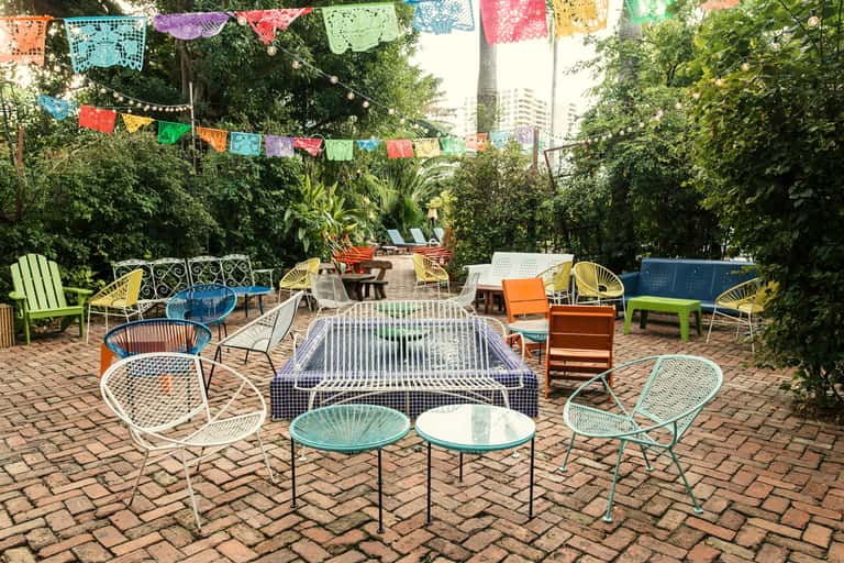 Bohemian courtyard with colorful papel picado, multicolored chairs, and lush greenery