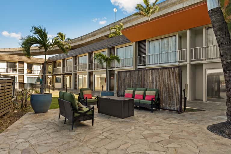 Contemporary courtyard with lounge seating, orange awning, and multi-story hotel building
