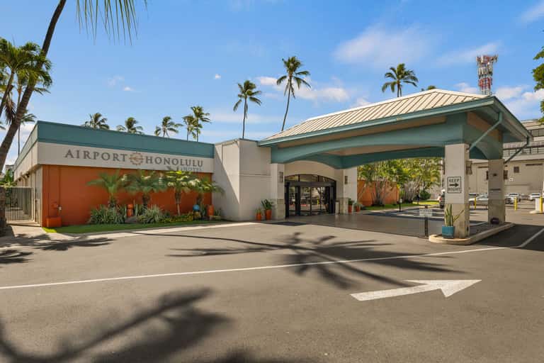 Airport Honolulu entrance with orange accent wall, teal roof, and palm tree landscaping