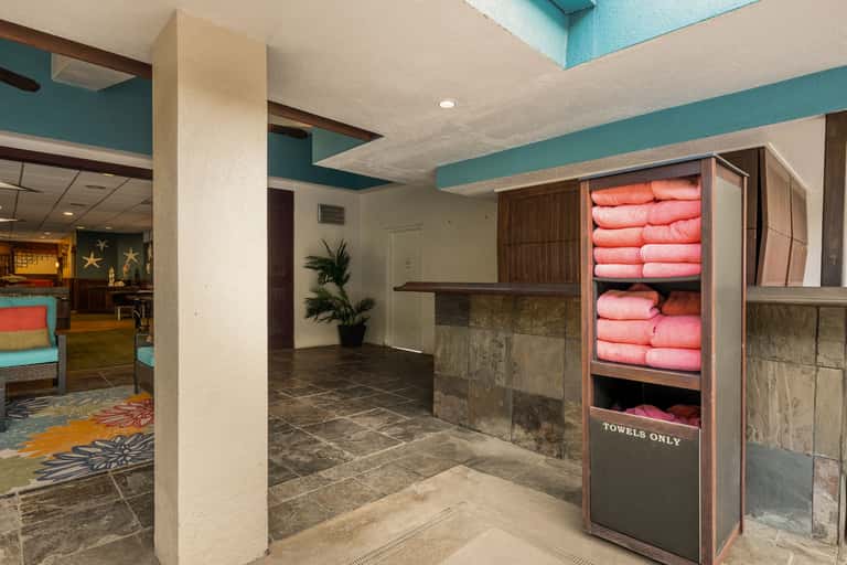 Hotel spa entrance with turquoise ceiling, towel storage cabinet displaying coral pink towels, and slate tile flooring