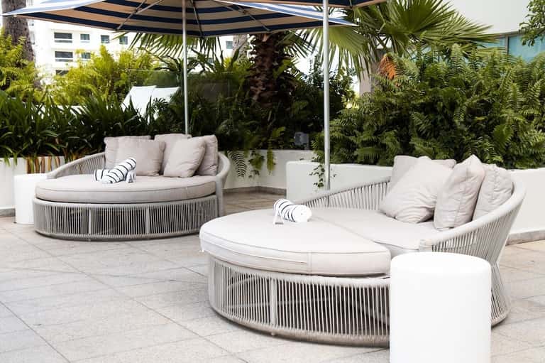 Modern lounge seating area with round white cushioned chairs, black and white umbrellas, and tropical plants