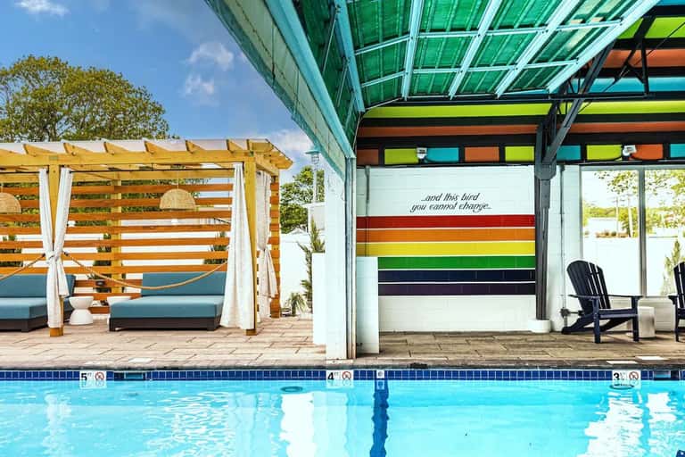 Outdoor pool area with wooden pergola lounge pavilion and colorful striped poolside backdrop