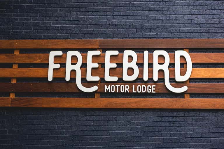 Freebird Motor Lodge sign on dark brick wall with wooden beam detail