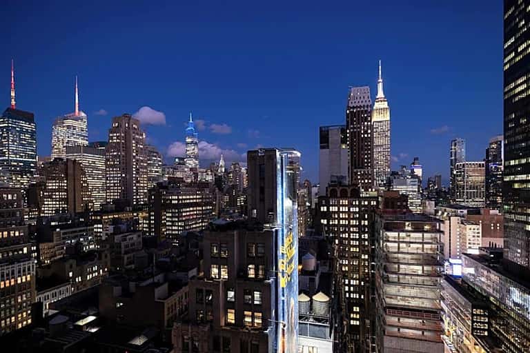 Manhattan skyline at dusk with illuminated skyscrapers, Empire State Building, and Chrysler Building visible