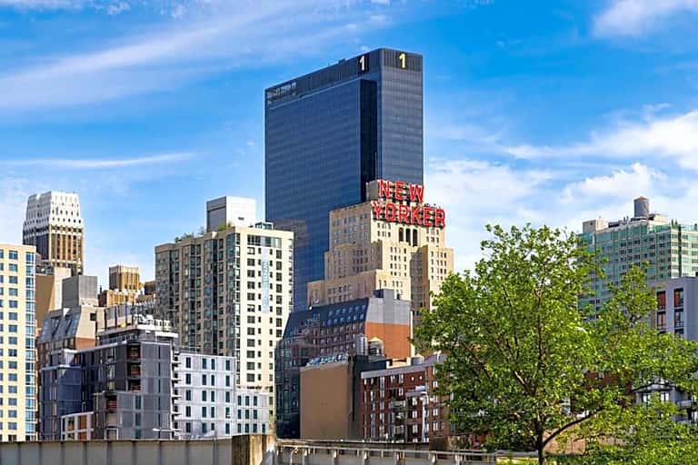 Daytime view of Manhattan buildings including the New Yorker Hotel with neon sign and surrounding architecture
