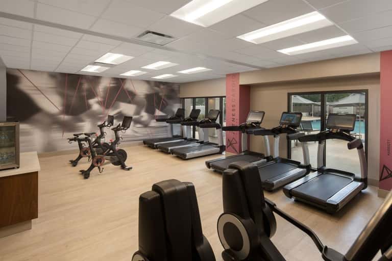 Fitness center with treadmills, stationary bikes, and exercise equipment on wooden flooring