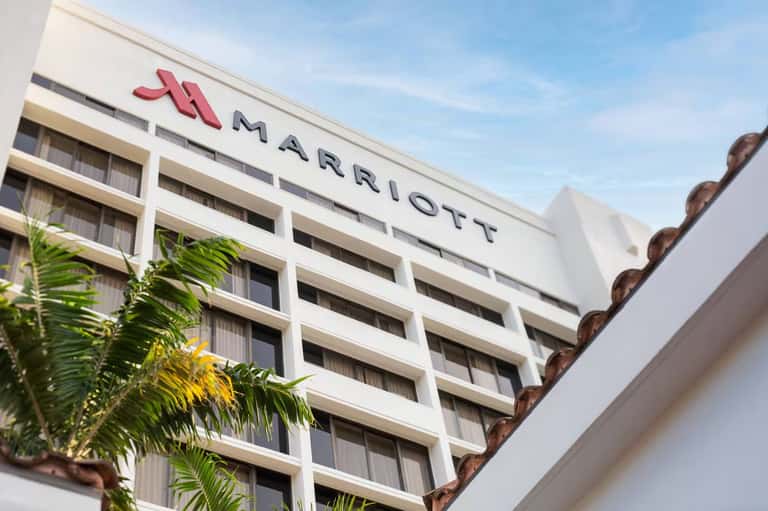 Marriott hotel exterior facade with white and beige building and palm trees below