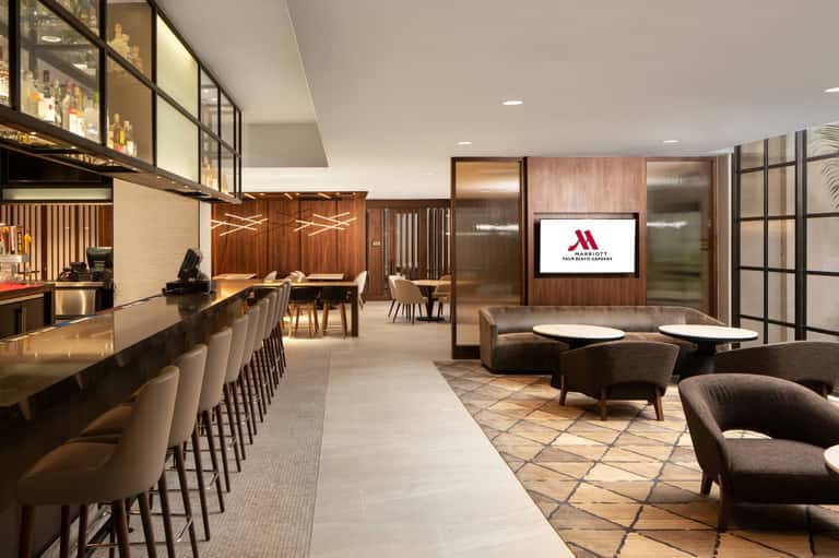 Contemporary hotel lobby bar and lounge with wood paneling, modern furniture, and ambient lighting