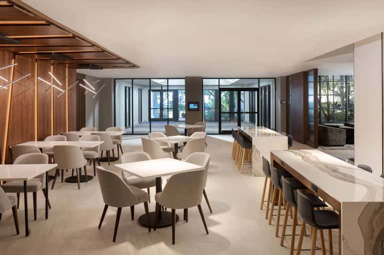 Bright hotel cafe or restaurant interior with natural light, casual seating, and outdoor terrace access