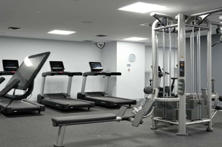 Fitness center with treadmills, weight bench, and cable machines in a bright, well-lit space