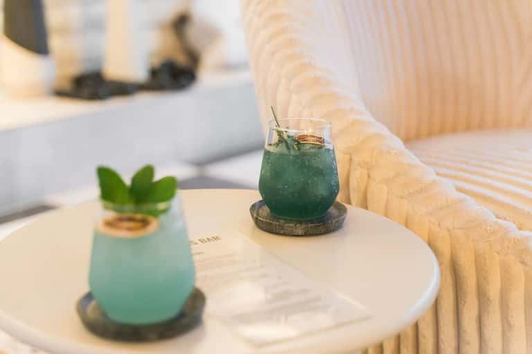 Cocktails with mint garnish on a table by a modern resort lounge area