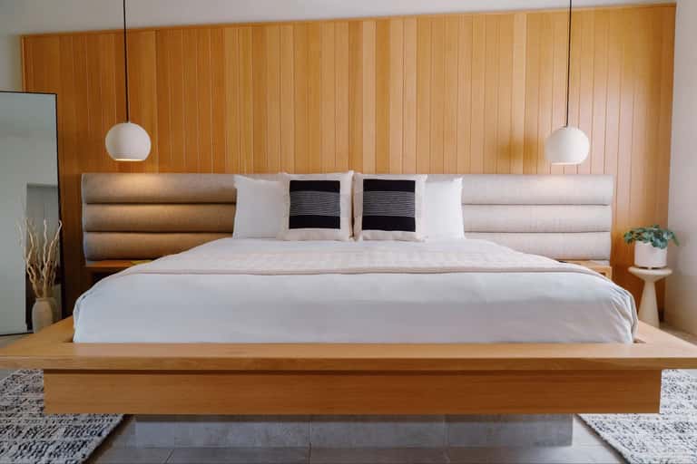 Contemporary bedroom with wood paneling, upholstered headboard, and pendant lights