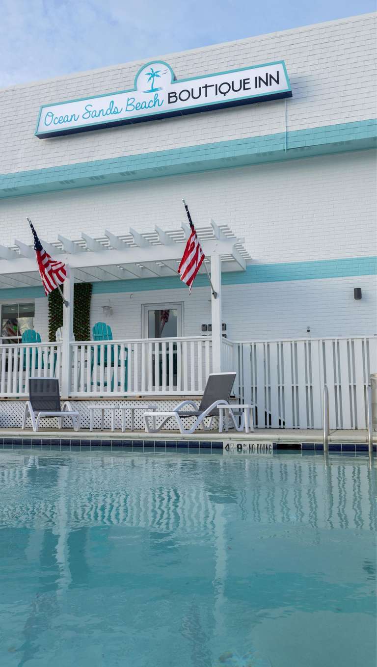 Ocean Sands Beach Boutique Inn entrance with turquoise trim and poolside flags