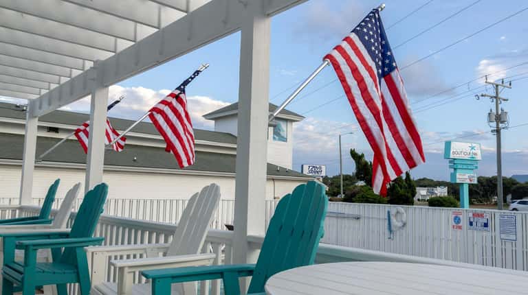 Beachfront porch with turquoise and white Adirondack chairs and American flags
