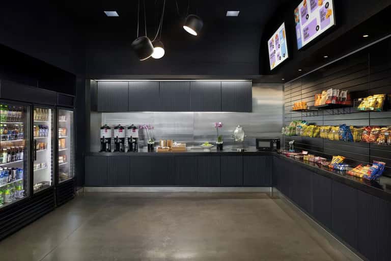Modern convenience store interior with black finishes, refrigerated cases, stocked shelves, and pendant lighting