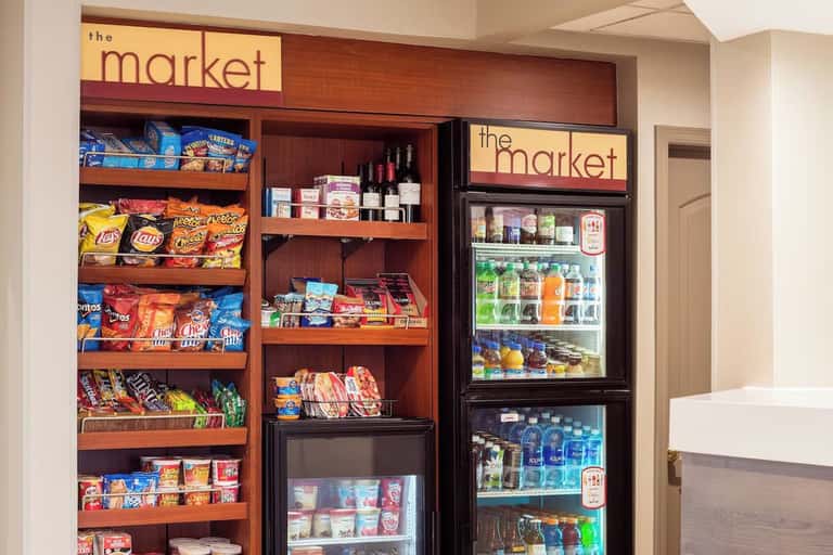 Hotel market shop displaying snacks, beverages, wine bottles, and refrigerated drinks with branded signage