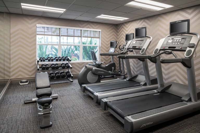 Fitness center with treadmills, stationary bikes, dumbbells, and chevron-patterned accent wall