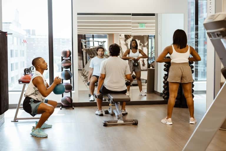 Group fitness class with participants doing strength training exercises in a high-rise gym with city views