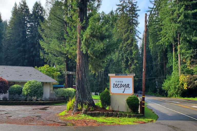 Casa Secoya resort sign at entrance with tall redwood trees lining the driveway