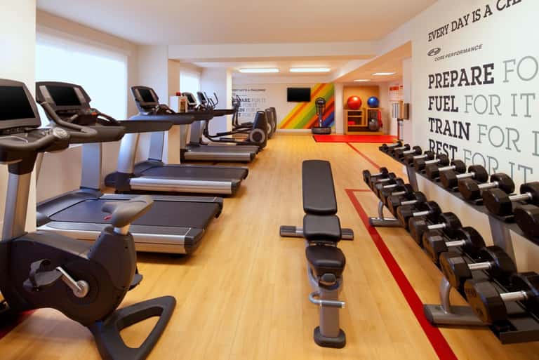Modern fitness center with treadmills, exercise bikes, dumbbells, and motivational wall signage