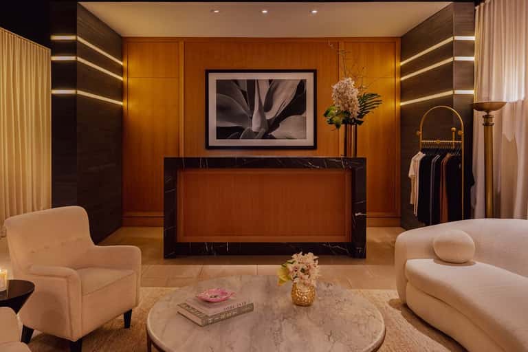Luxury spa reception desk with wood paneling, marble counter, flowers, and modern seating