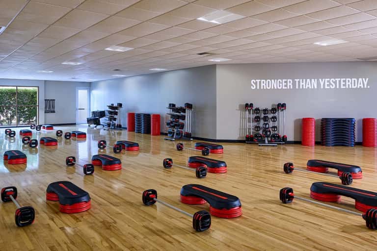 Group fitness studio with wooden floors, step platforms, and motivational wall text
