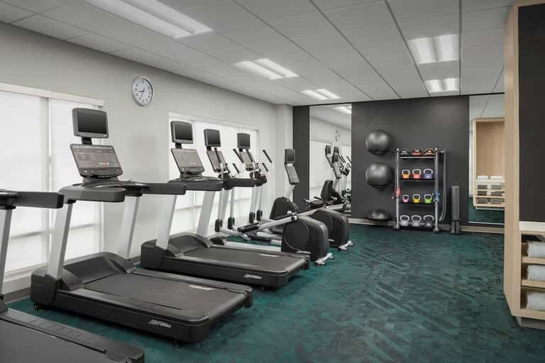 Fitness center with treadmills, stationary bikes, exercise equipment, and teal carpeting