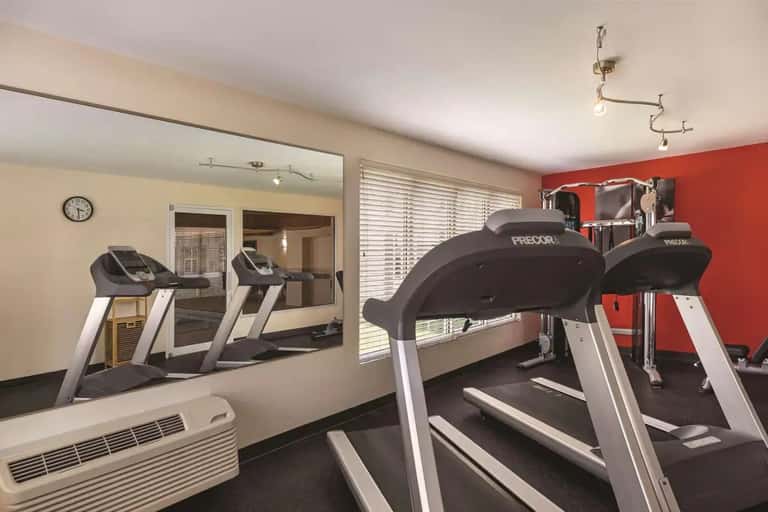 Hotel fitness center with treadmills and exercise equipment facing a mirrored wall
