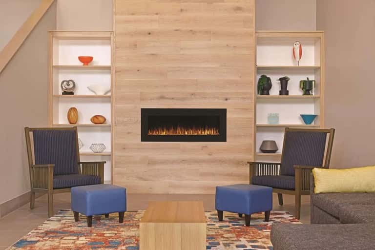 Lobby lounge with fireplace, wood accent wall, built-in shelving, and upholstered chairs