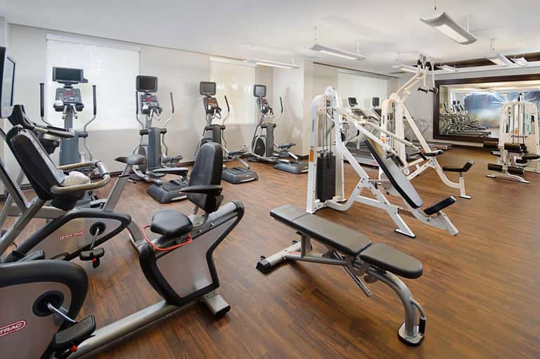 Modern gym with stationary bikes, exercise equipment, treadmills, and wood flooring