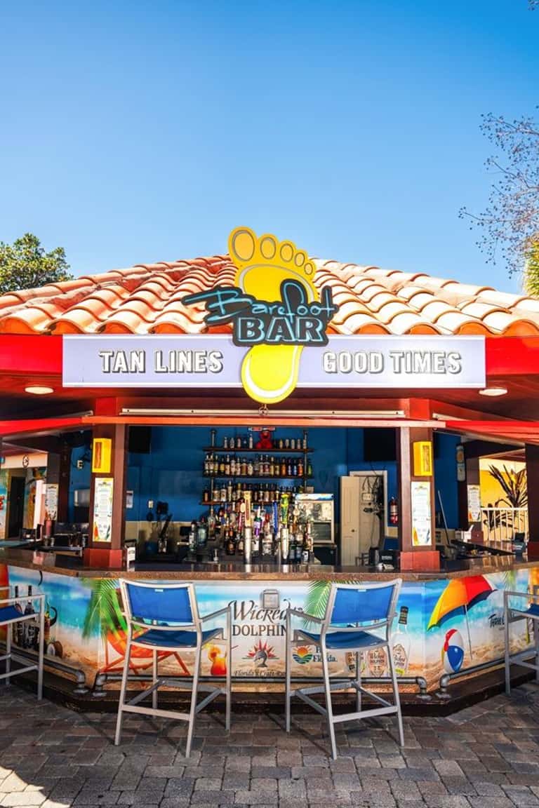 Colorful beach bar with blue and red exterior, tan lines signage, tropical setting