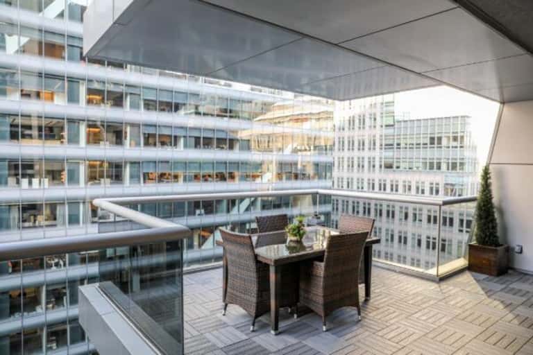 Rooftop terrace with dining table and chairs overlooking urban cityscape and surrounding buildings