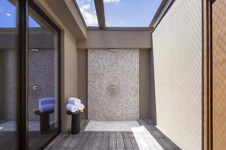 Modern spa shower with skylight, tile walls, rolled towels, and indoor-outdoor design