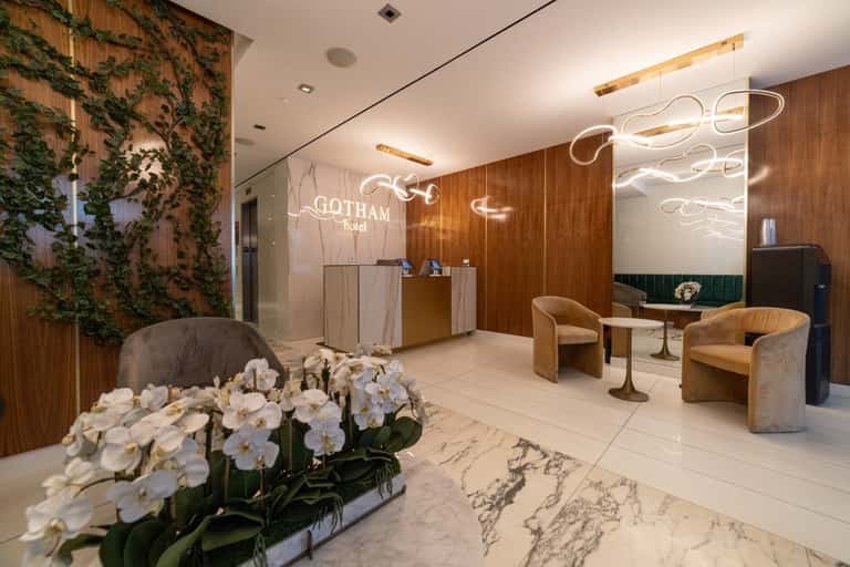 Modern hotel lobby with wood paneling, neon sign, living wall, and contemporary seating area